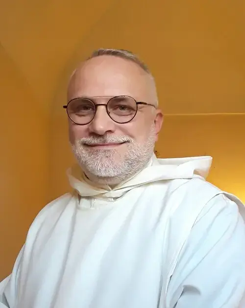 Ritratto di Padre Natale Brescianini, sorridente in abito religioso su sfondo chiaro.