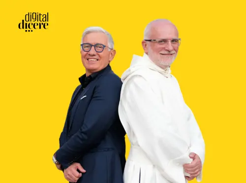 Due uomini sorridenti fotografati schiena contro schiena su sfondo giallo: a sinistra Fausto Turco in abito nero, a destra Padre Natale Brescianini in saio bianco. In alto a sinistra il logo Digital Dicere.